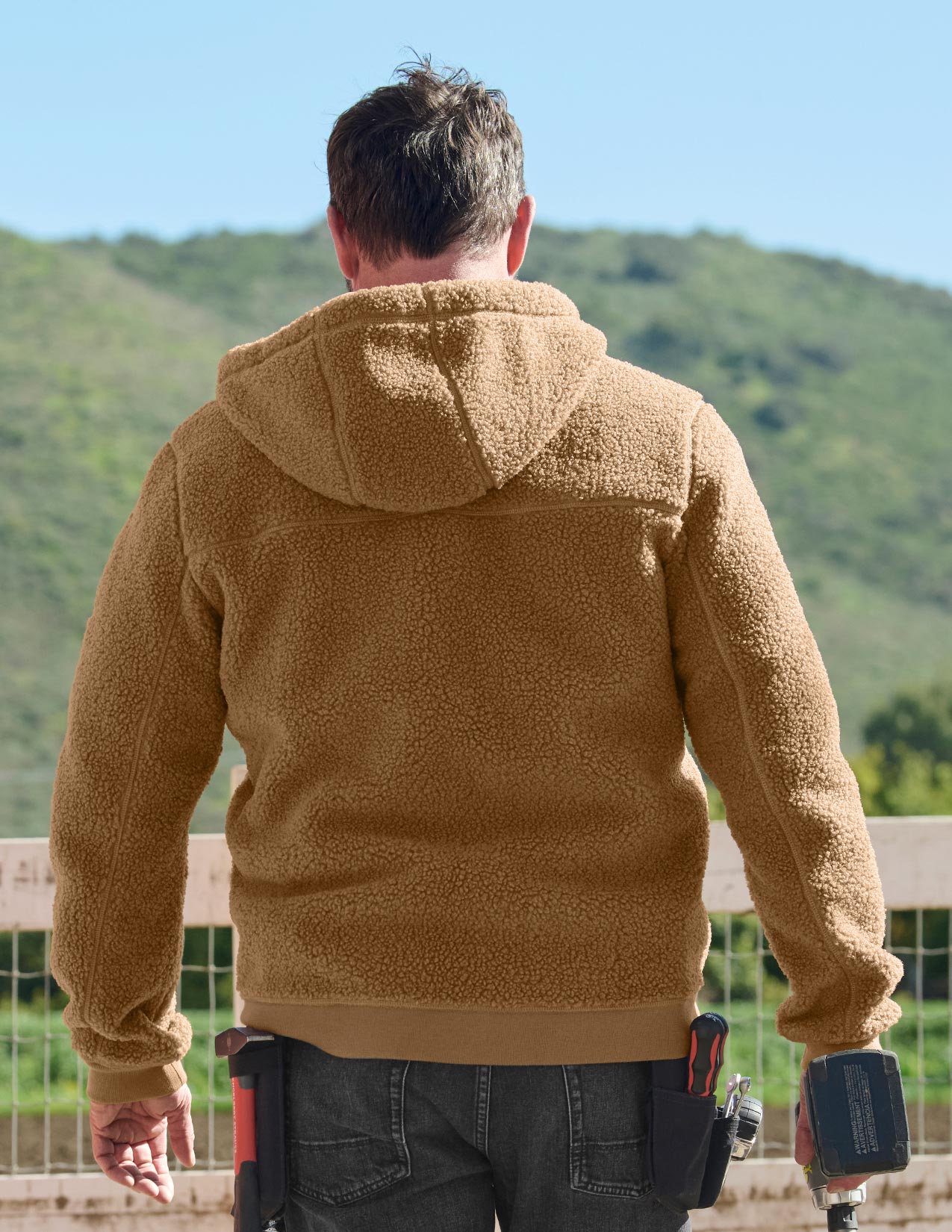 Man wearing a brown fleece jacket with a scenic background