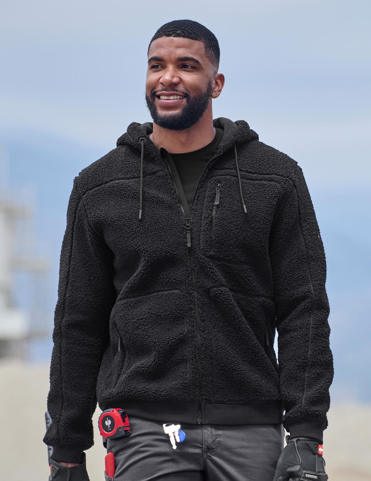 Man wearing a black fleece jacket with a blurred background