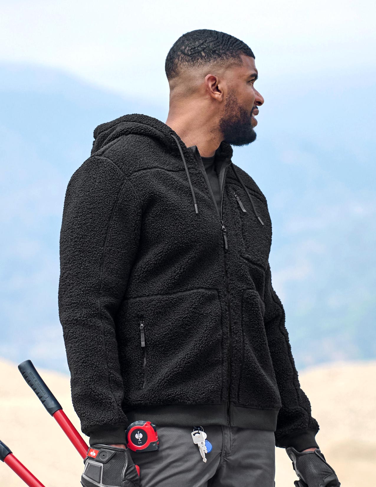 Man wearing a black fleece jacket outdoors with a blurred background