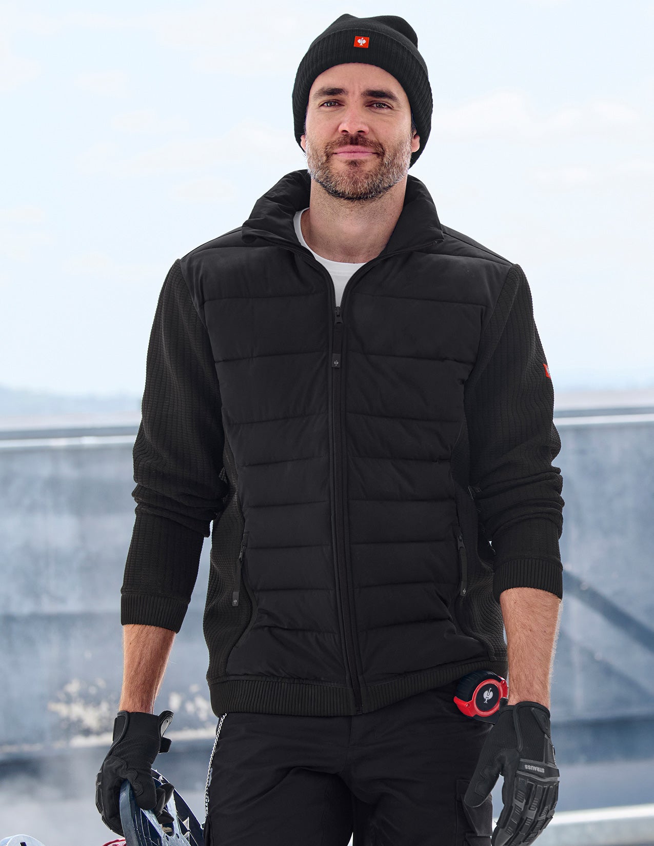 Man wearing a black puffer jacket with a blurred background.