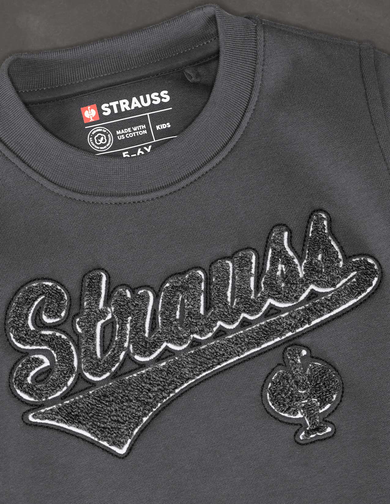 Gray sweatshirt with 'Strauss' branding and logo on a dark background