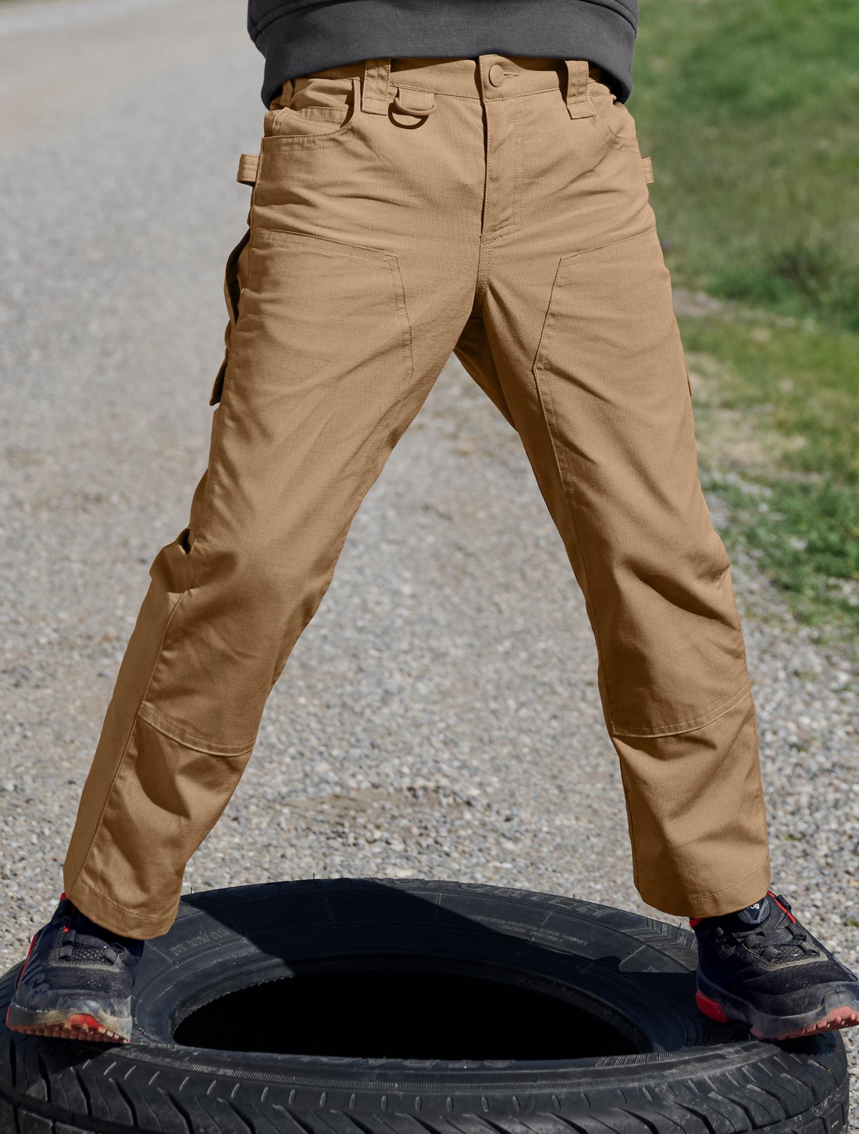 Child wearing tan pants standing on a tire with a blurred background