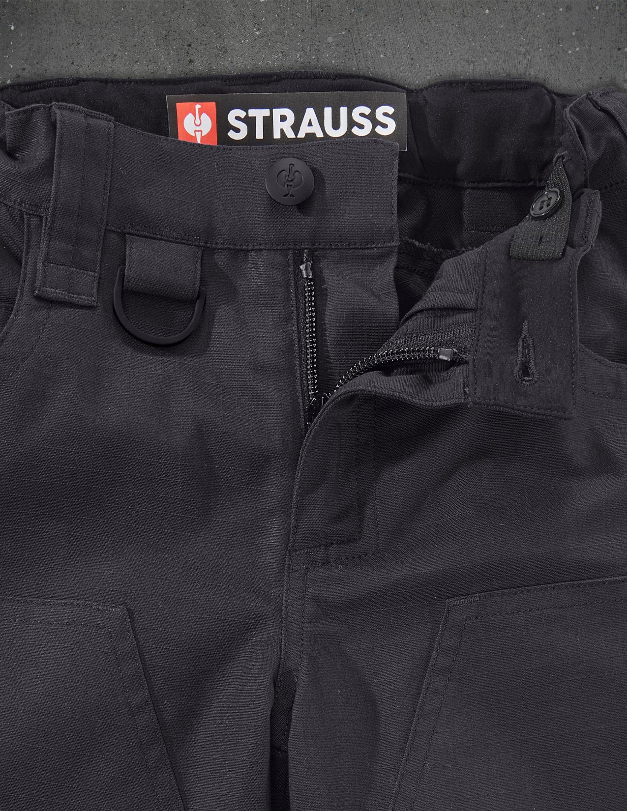 Black Strauss pants with a close-up of the brand logo on the waistband.