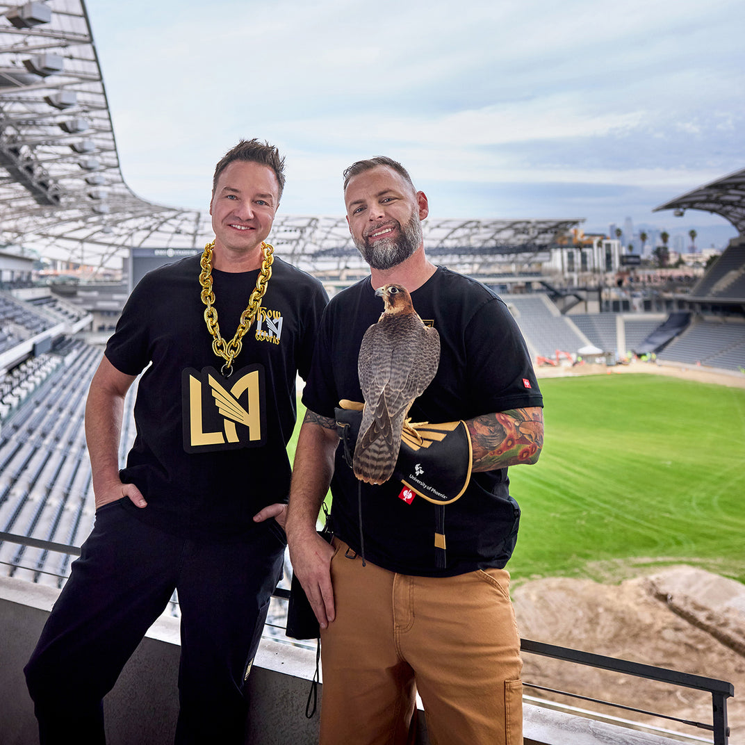 Henning Strauss and other person with a falcon wearing lafc wear in front of the LAFC Stadium