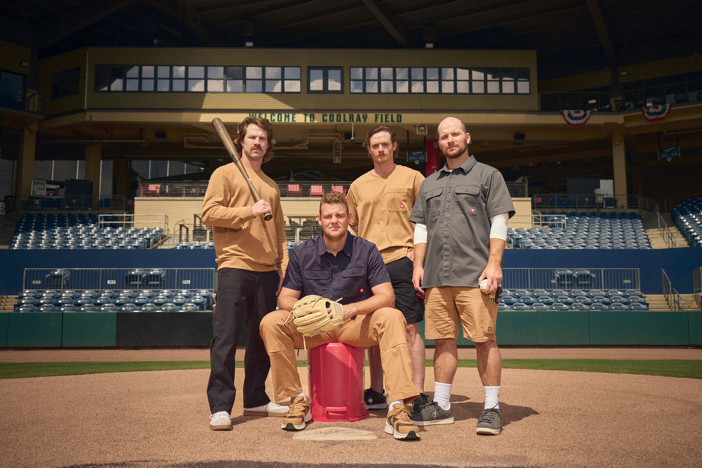 Four men stand on home plate in Strauss Workwear