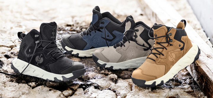 Four pairs of soft-toe work boots in black, navy blue, gray, and tan are displayed on weathered concrete steps.