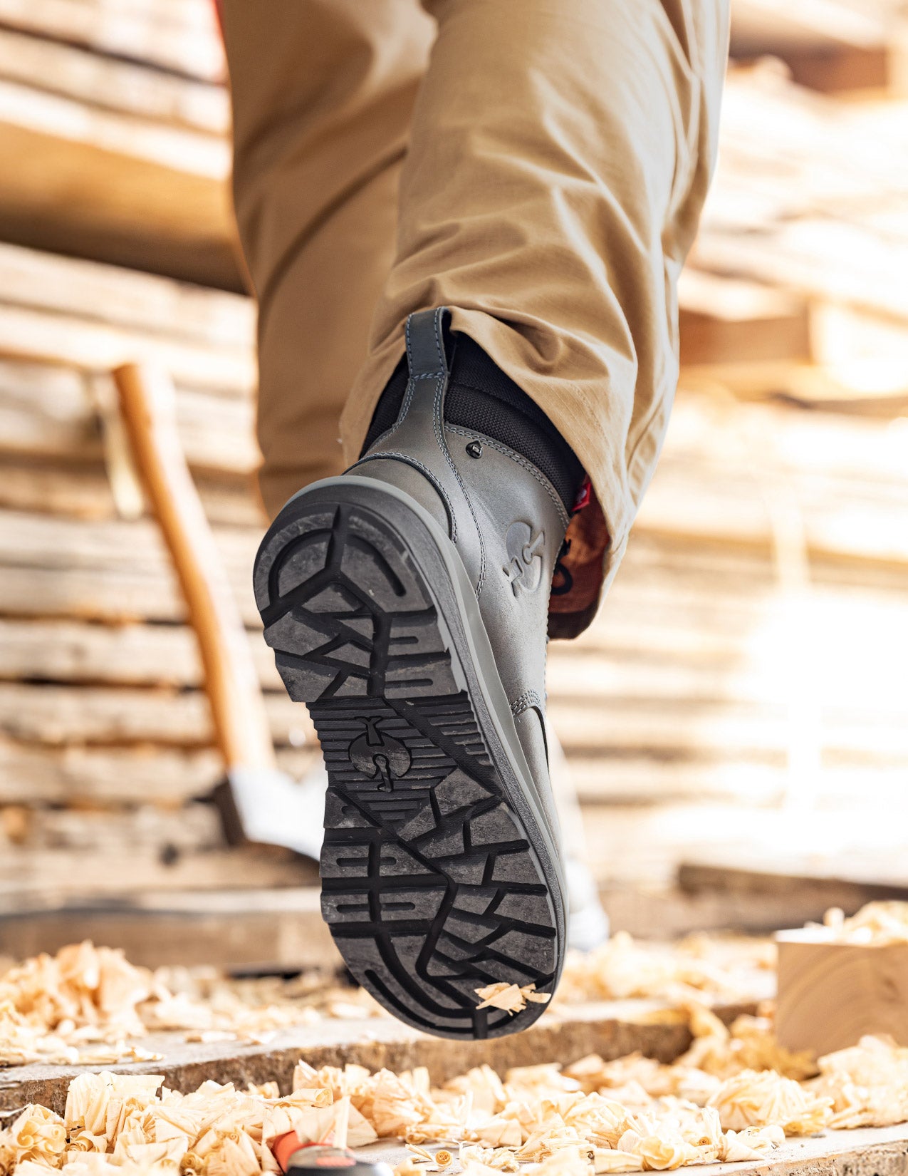 Close-up of a foot wearing a gray shoe with a textured sole on a wooden floor.
