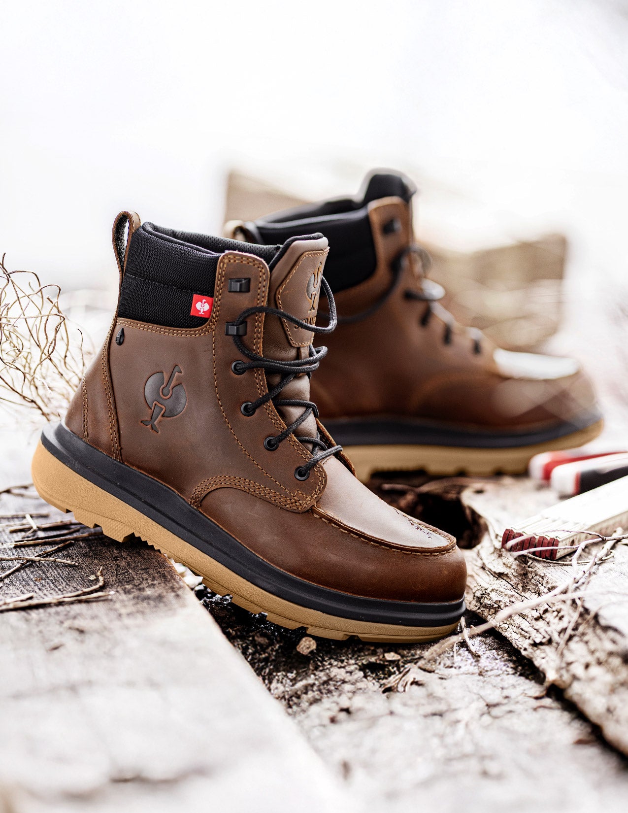 Brown leather boots with black soles on a textured surface