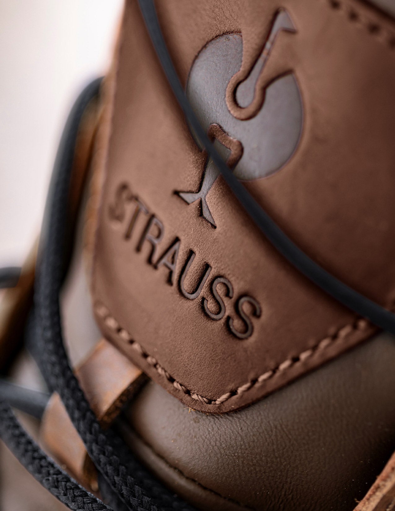 Close-up of a brown leather boot with 'Strauss' branding.