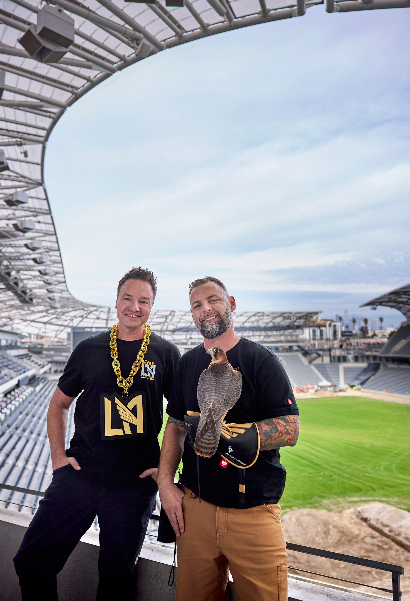 Henning Strauss and other person with a falcon wearing lafc wear in front of the LAFC Stadium