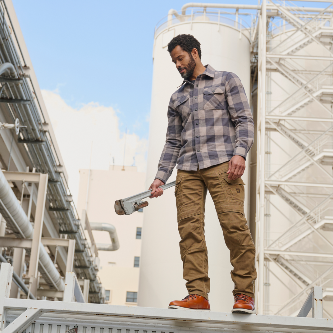Man holding a wrench in front of industrial tanks