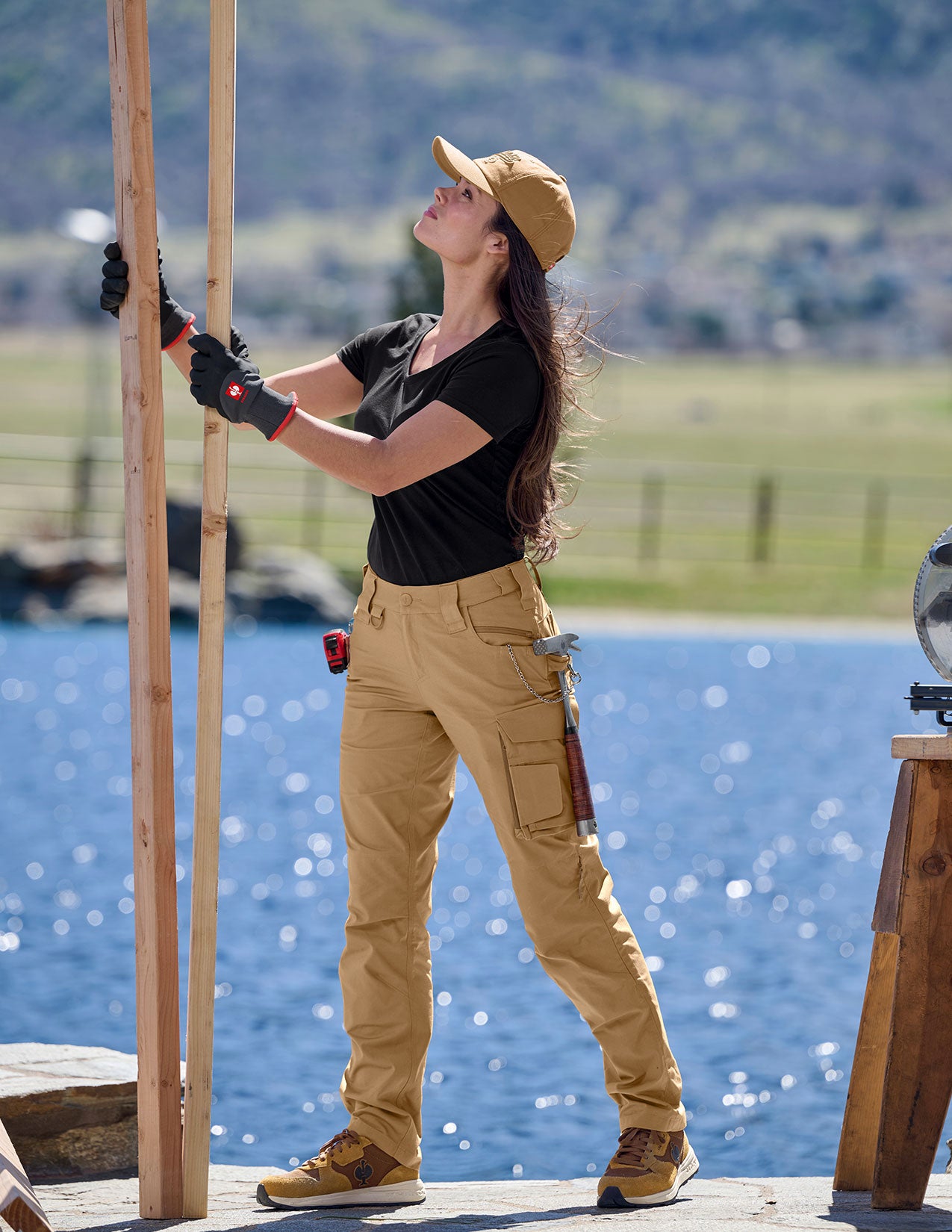 Person in work attire with tools, standing by a body of water.
