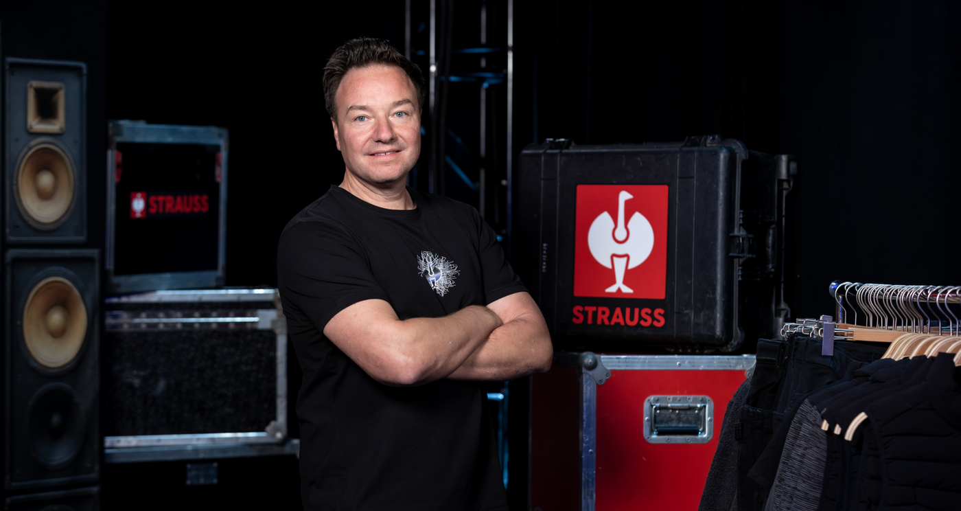 Henning Strauss standing in a room with musical equipment and Strauss branding.