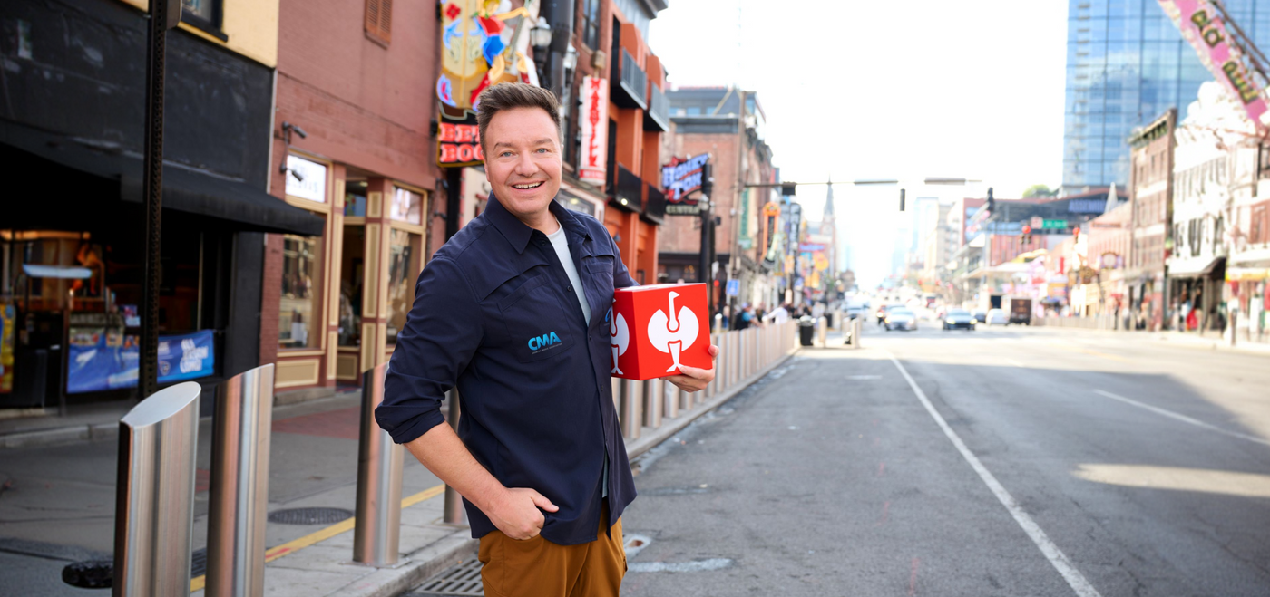 An image of CEO Henning Strauss standing on a road in Nashville, holding a red Strauss cube in his hand.