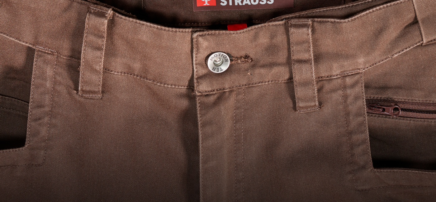 Close-up of brown pants with a button and zipper, featuring the brand 'Strauss'.