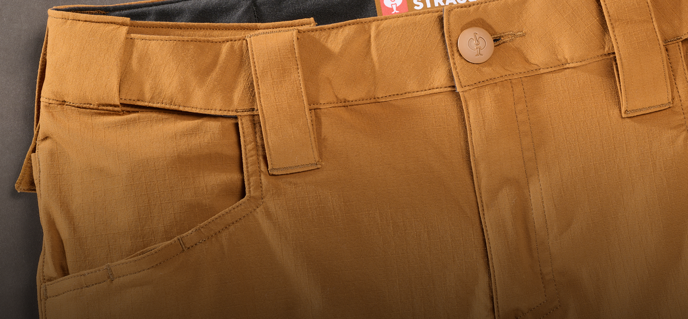 Close-up of brown ripstop pants with a brand label on a gray background