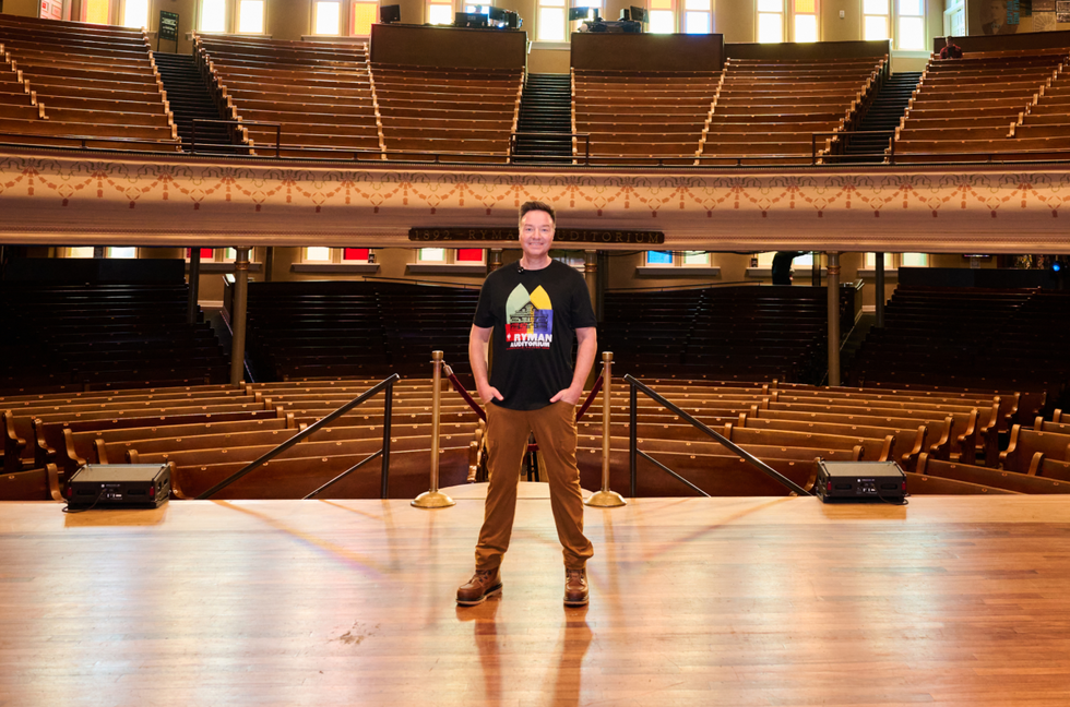 A picture of Henning Strauss standing on the stage at the Ryman Auditorium