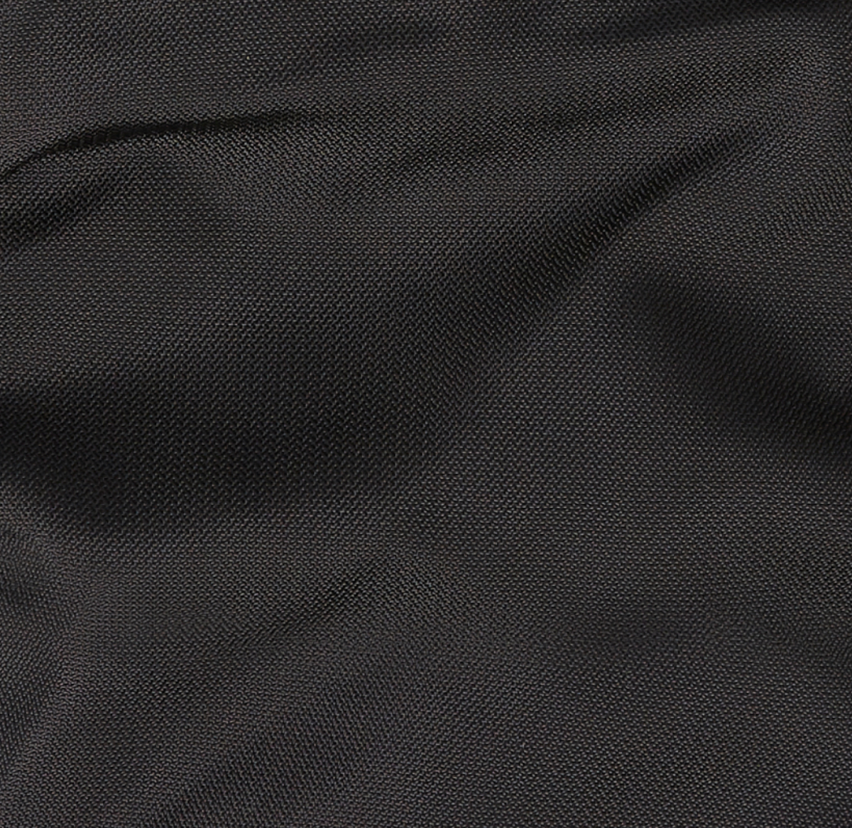 A close-up of dark, textured fabric with visible woven patterns and slight folds, creating a subtle play of light and shadow across the surface.