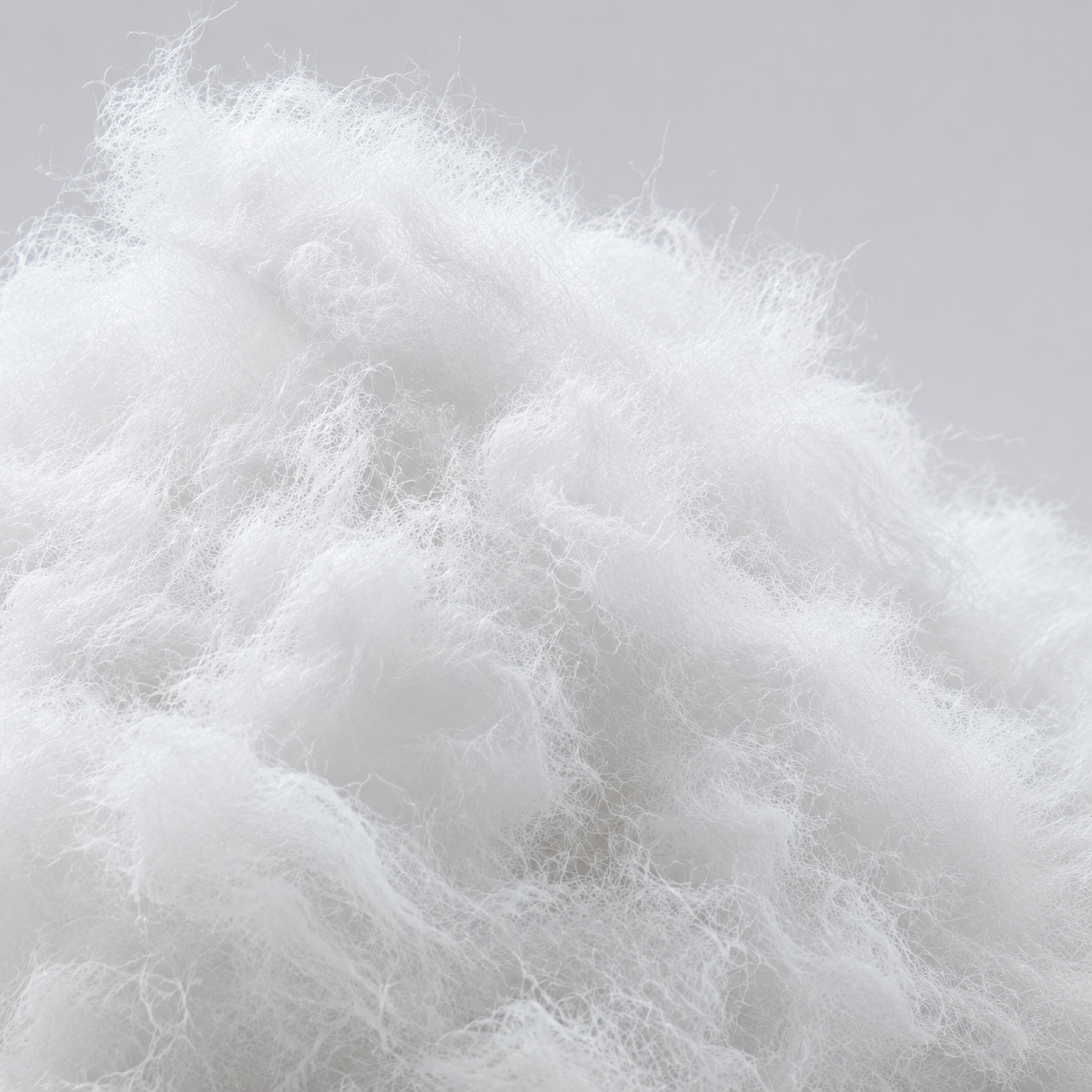 White fluffy isofill fiber or stuffing material filling most of the frame against a light gray background.