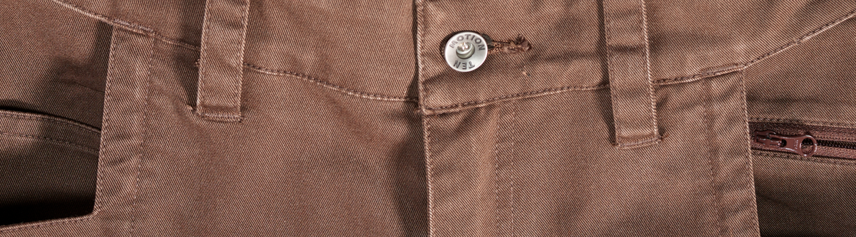 Close-up of brown pants showing the waistband, a button, belt loops, stitching, and part of a zipper pocket on the side.