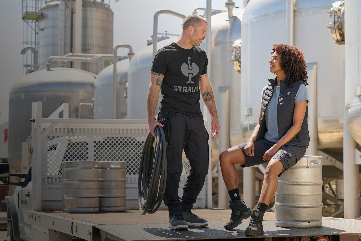 Man carrying hose talks to a woman at a factory