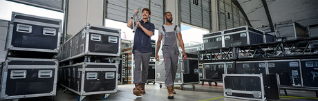Two men wearing workwear and carrying tools