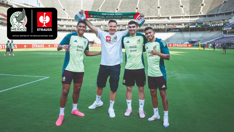 CEO Henning Strauss standing next to soccer players in the middle of a soccer stadium 