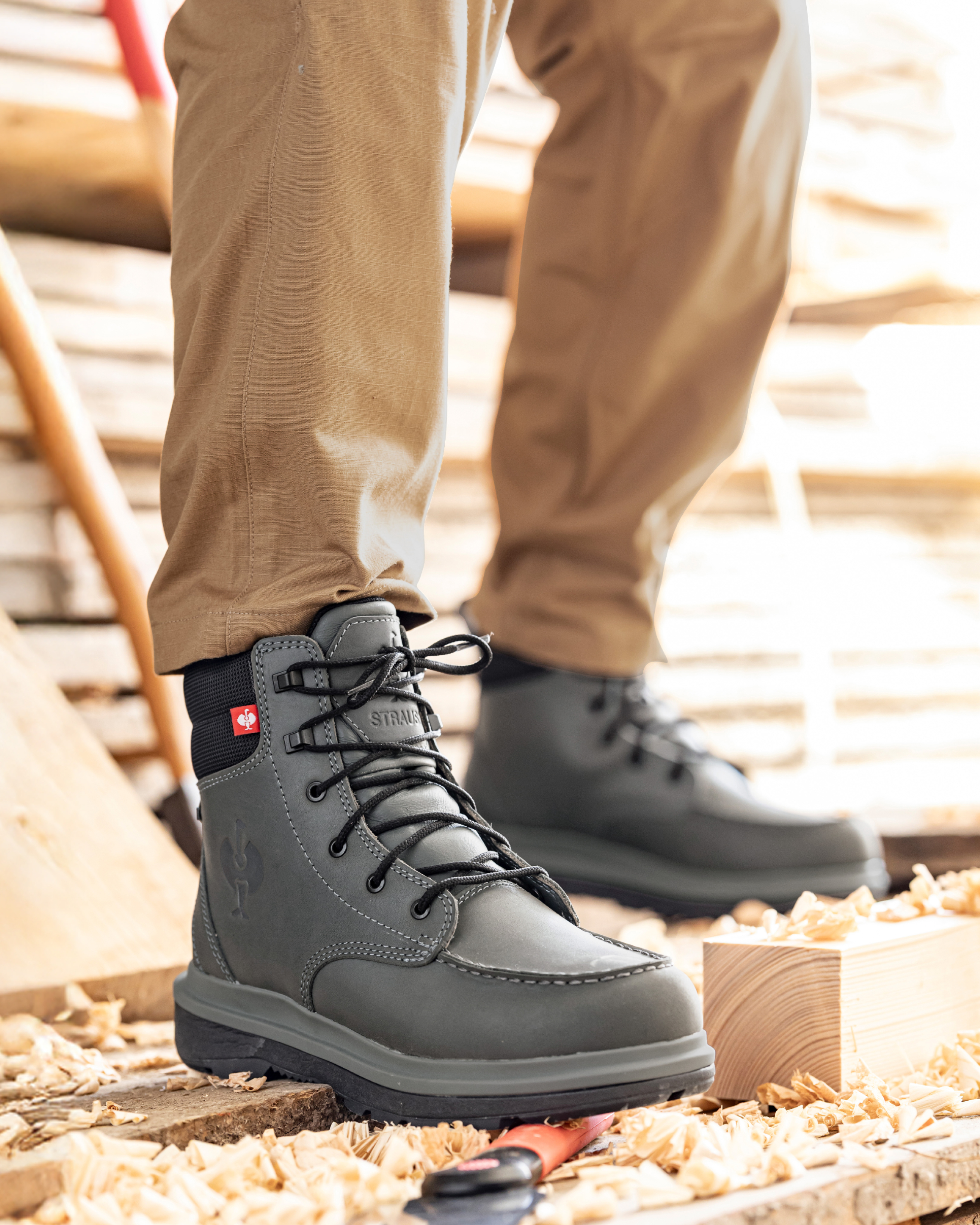 Gray work boots with black soles worn by a person on a wooden floor.