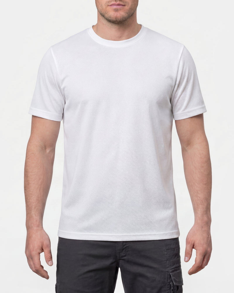A model wears the STRAUSS Performance T-Shirt in white with tan work pants and work boots in a studio product scene