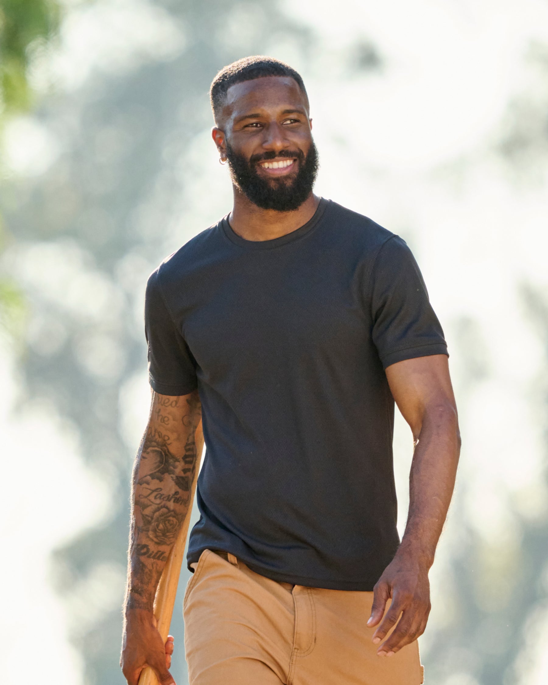 A worker wears the STRAUSS Performance T-Shirt in black with tan work pants on a sunny jobsite
