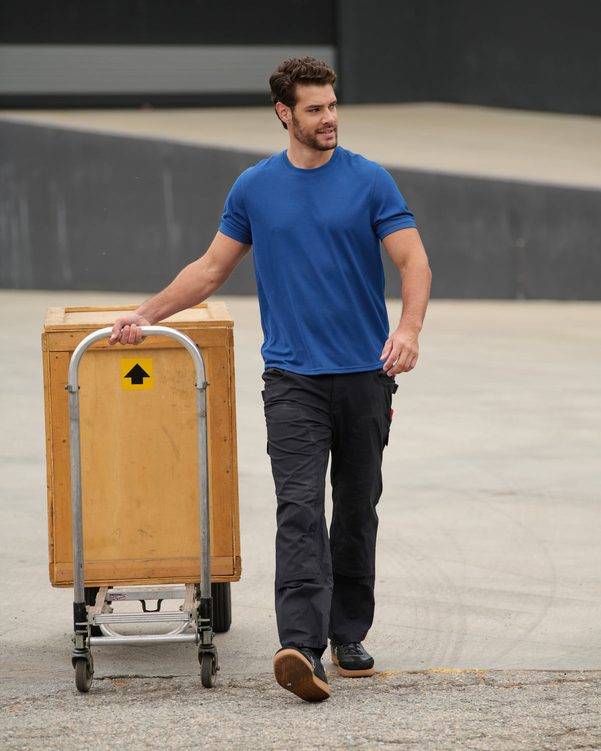 A worker wears the STRAUSS Performance T-Shirt in royal blue while working in a field