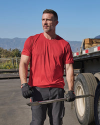 A worker wears the STRAUSS Performance T-Shirt in fire red on a sunny jobsite