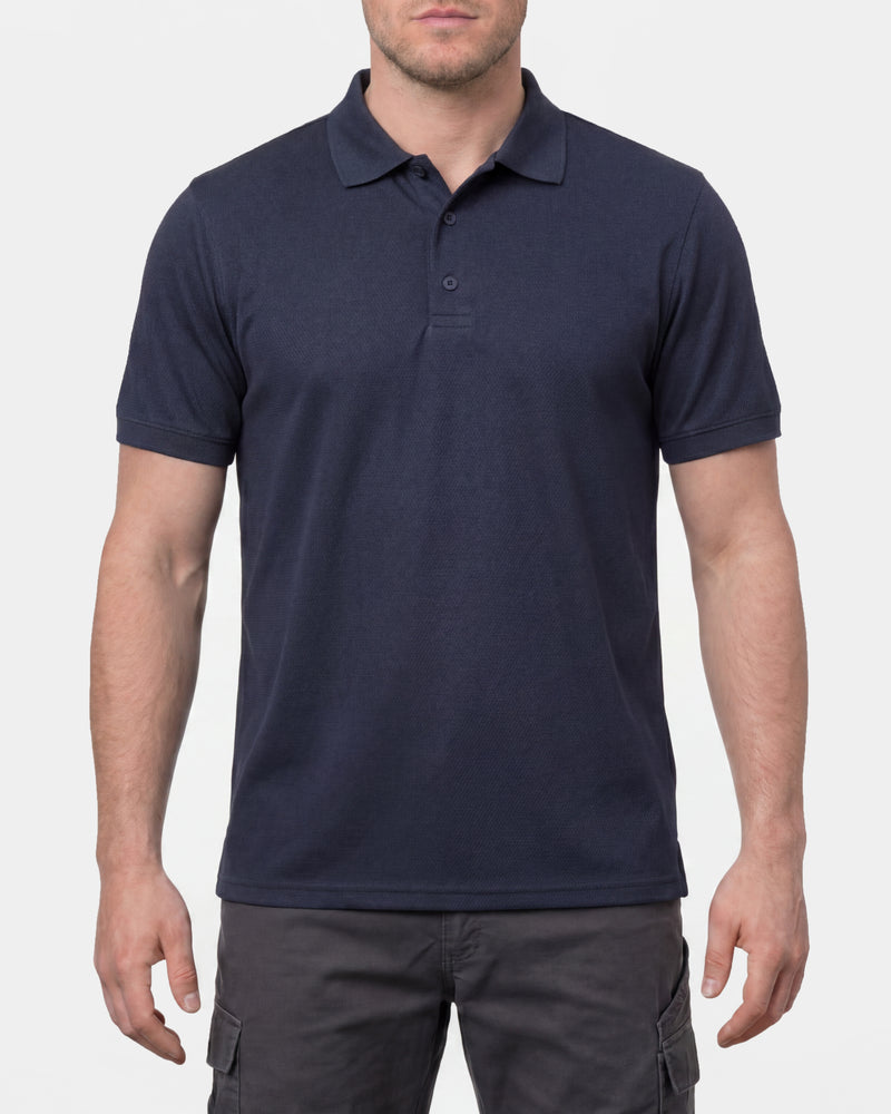 A model wears the STRAUSS Performance Polo Shirt in nero blue in a studio product scene