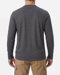A model wears the STRAUSS Performance Long Sleeve Shirt in carbon gray with tan work pants and work boots, showing the shirt fit