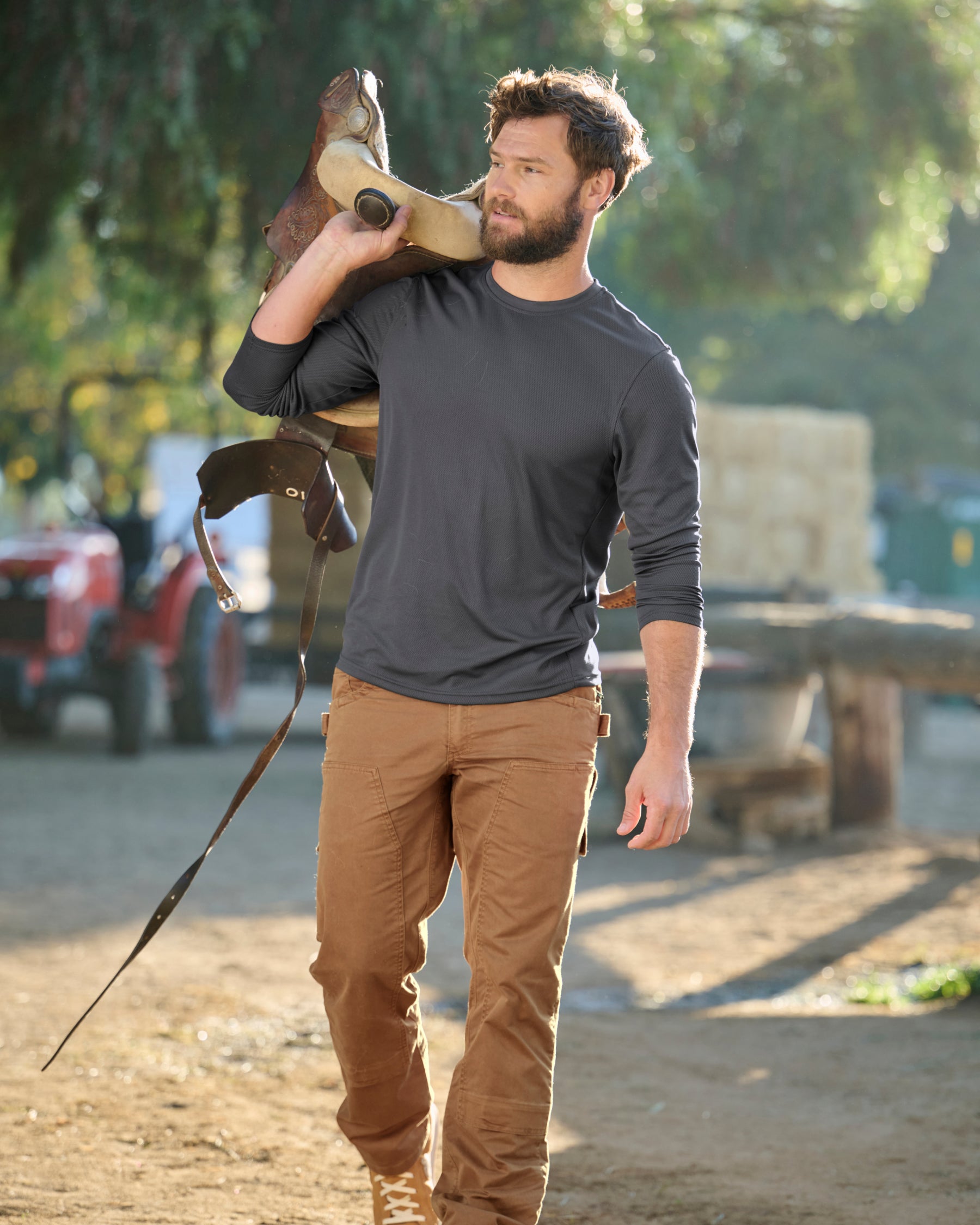 A worker wears the STRAUSS Performance Long Sleeve Shirt in carbon gray with tan work pants while working in a field