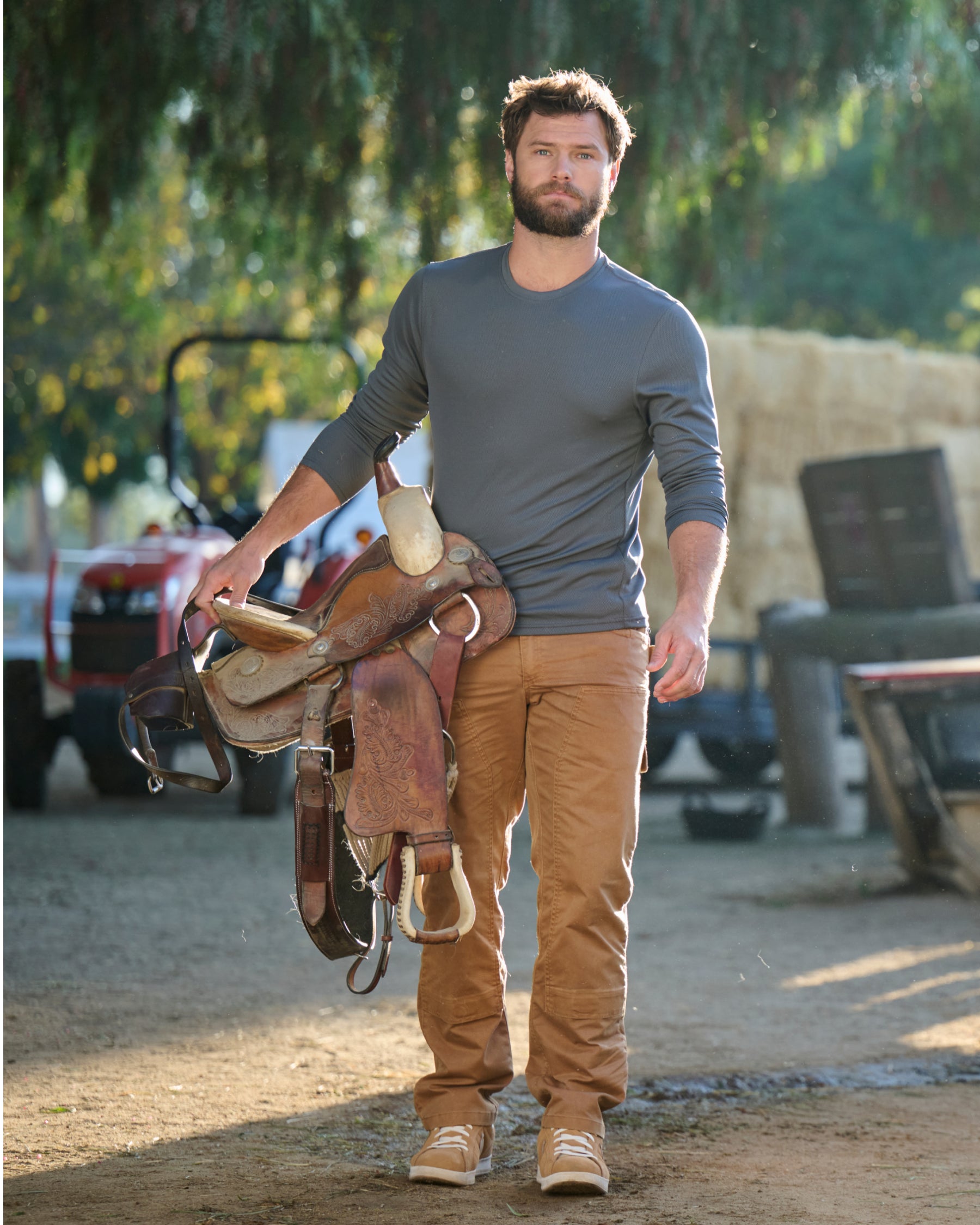 A worker wears the STRAUSS Performance Long Sleeve Shirt in carbon gray with tan work pants beside jobsite equipment