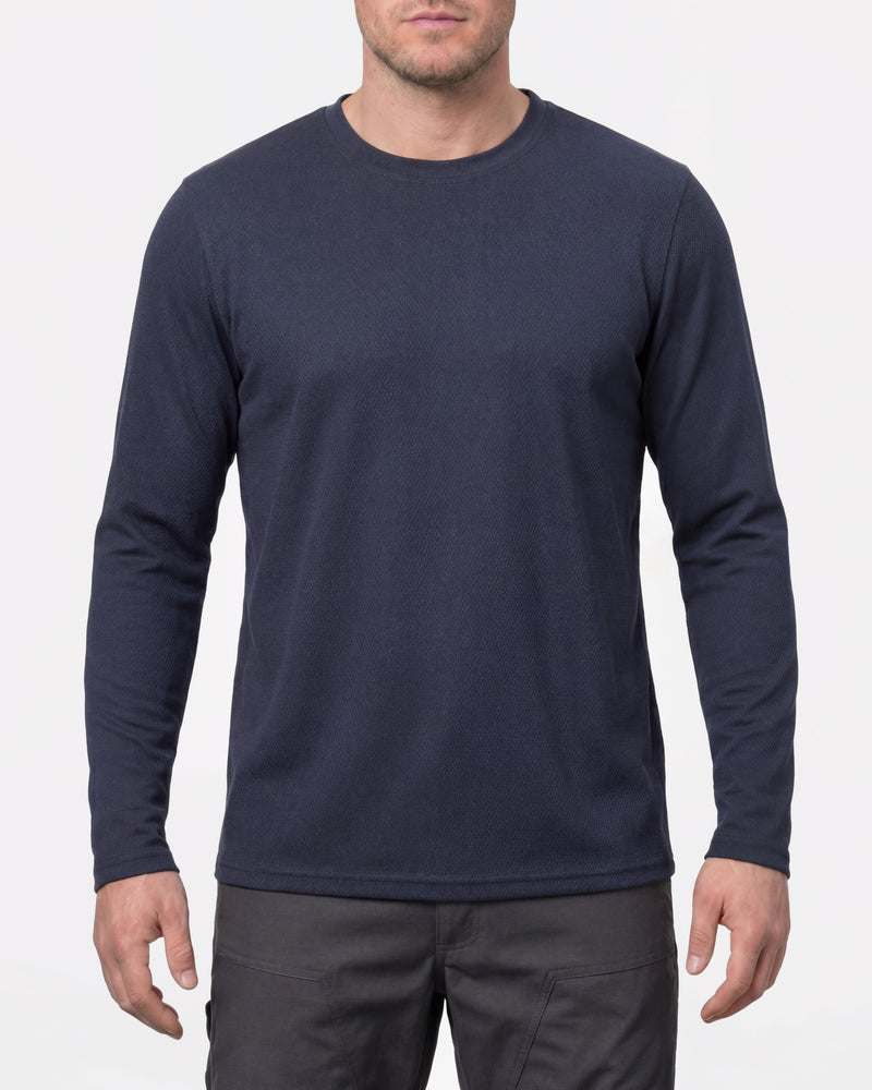 A model wears the STRAUSS Performance Long Sleeve Shirt in nero blue with tan work pants and work boots in a studio product scene