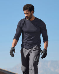 A worker wears the STRAUSS Performance Long Sleeve Shirt in nero blue with tan work pants on a sunny jobsite