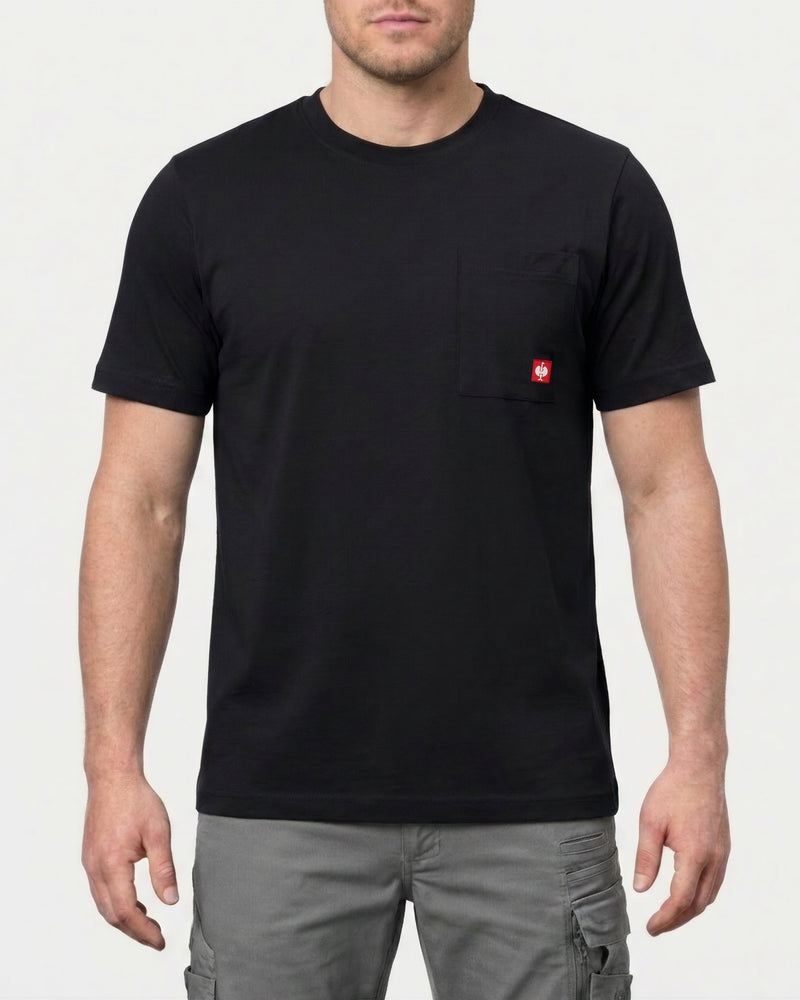 A model wears the STRAUSS Pocket T-Shirt e.s.iconic in black with work pants and work boots in a studio product scene