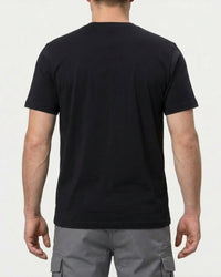 A model wears the STRAUSS Pocket T-Shirt e.s.iconic in black with work pants and work boots, showing the shirt fit