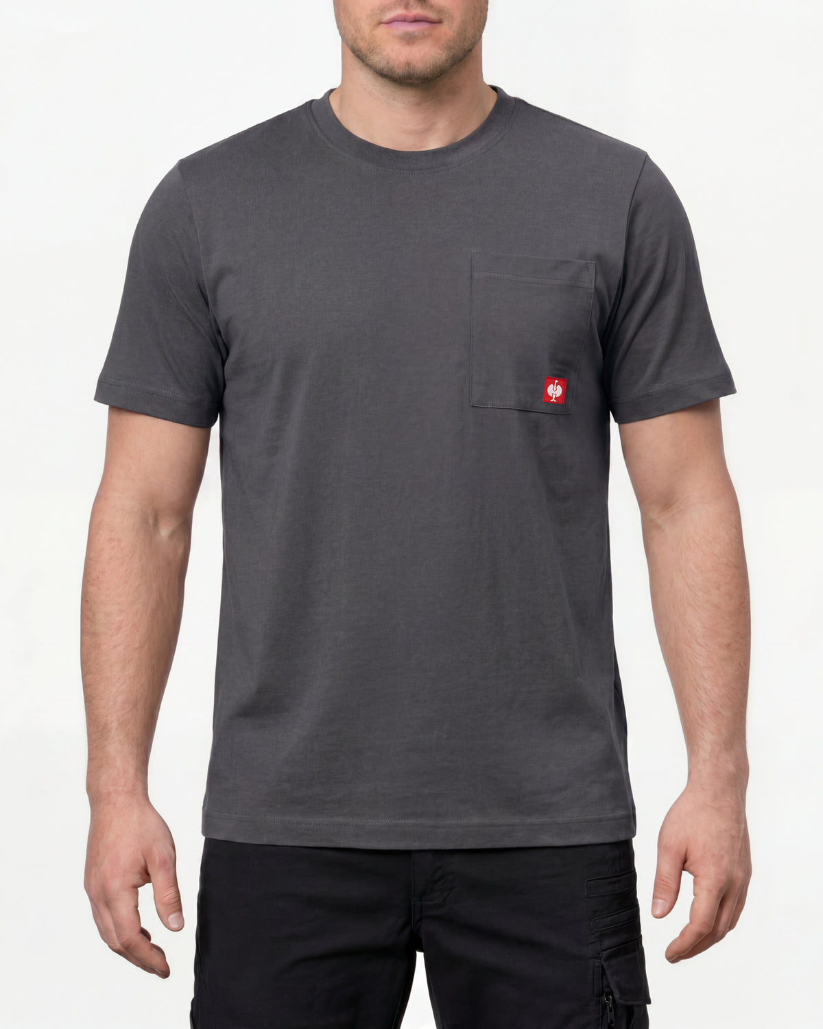A model wears the STRAUSS Pocket T-Shirt e.s.iconic in carbon gray with work pants and work boots in a studio product scene