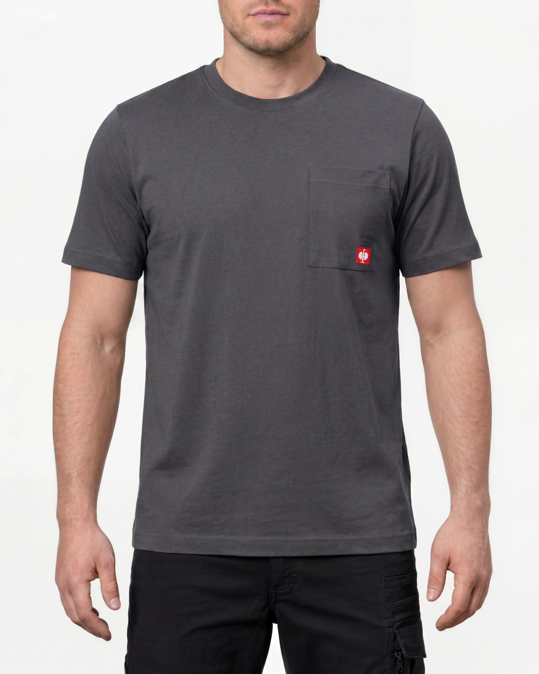 A model wears the STRAUSS Pocket T-Shirt e.s.iconic in carbon gray with work pants and work boots in a studio product scene