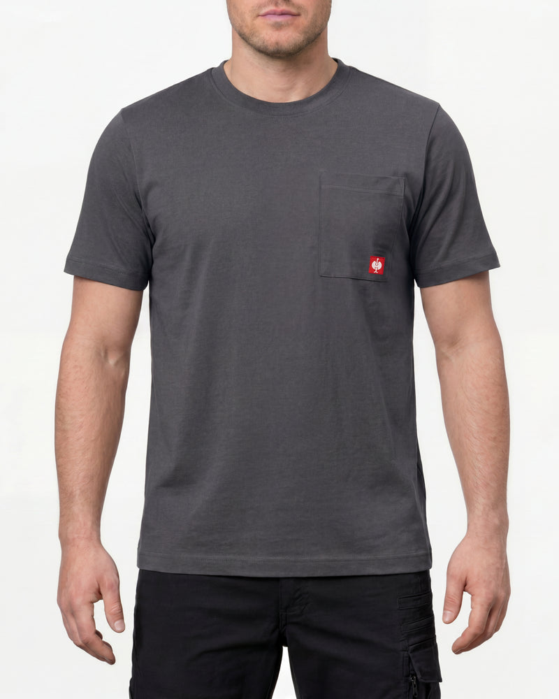 A model wears the STRAUSS Pocket T-Shirt e.s.iconic in carbon gray with work pants and work boots in a studio product scene