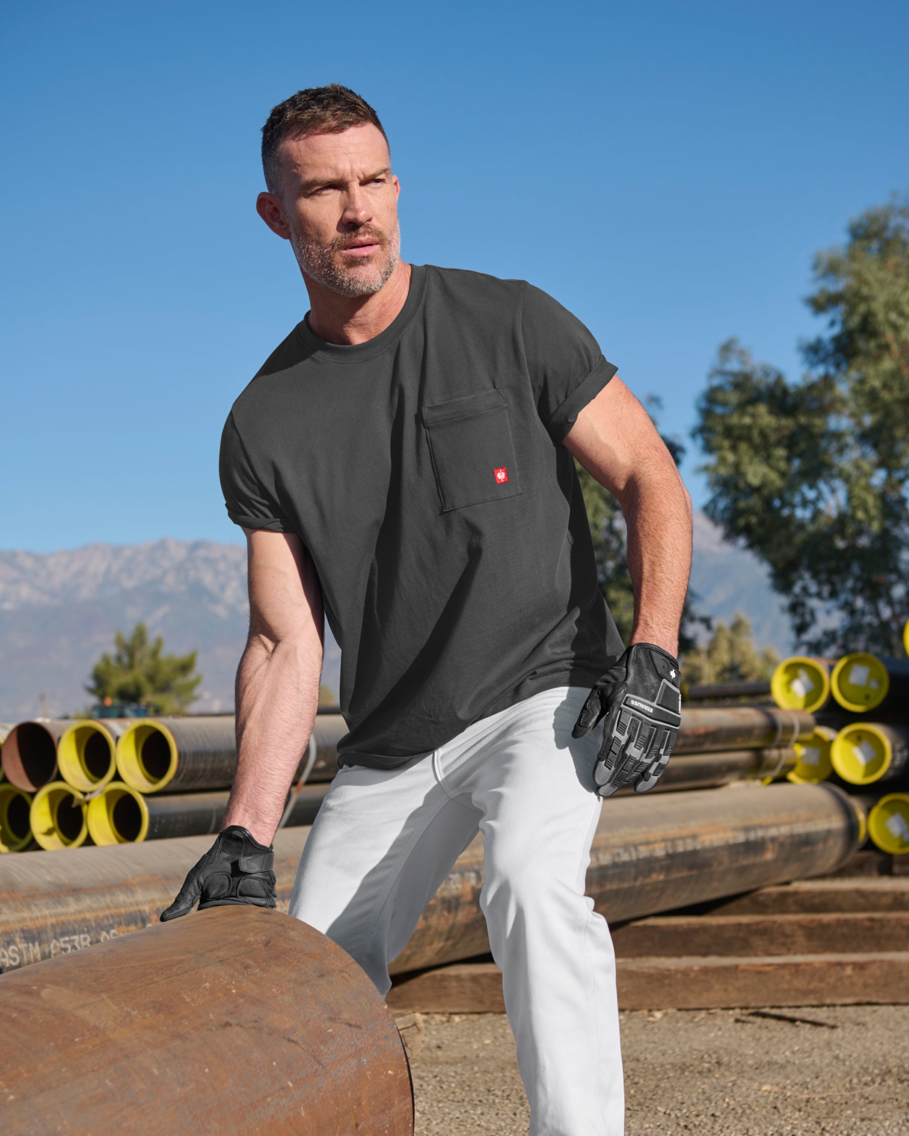 A worker wears the STRAUSS Pocket T-Shirt e.s.iconic in carbon gray with utility pants and work boots outside a shop