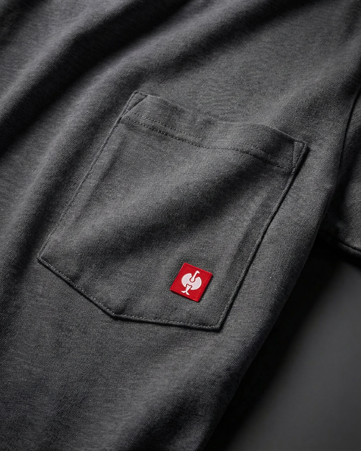 Close-up of the carbon gray STRAUSS Pocket T-Shirt e.s.iconic chest pocket with STRAUSS ostrich logo