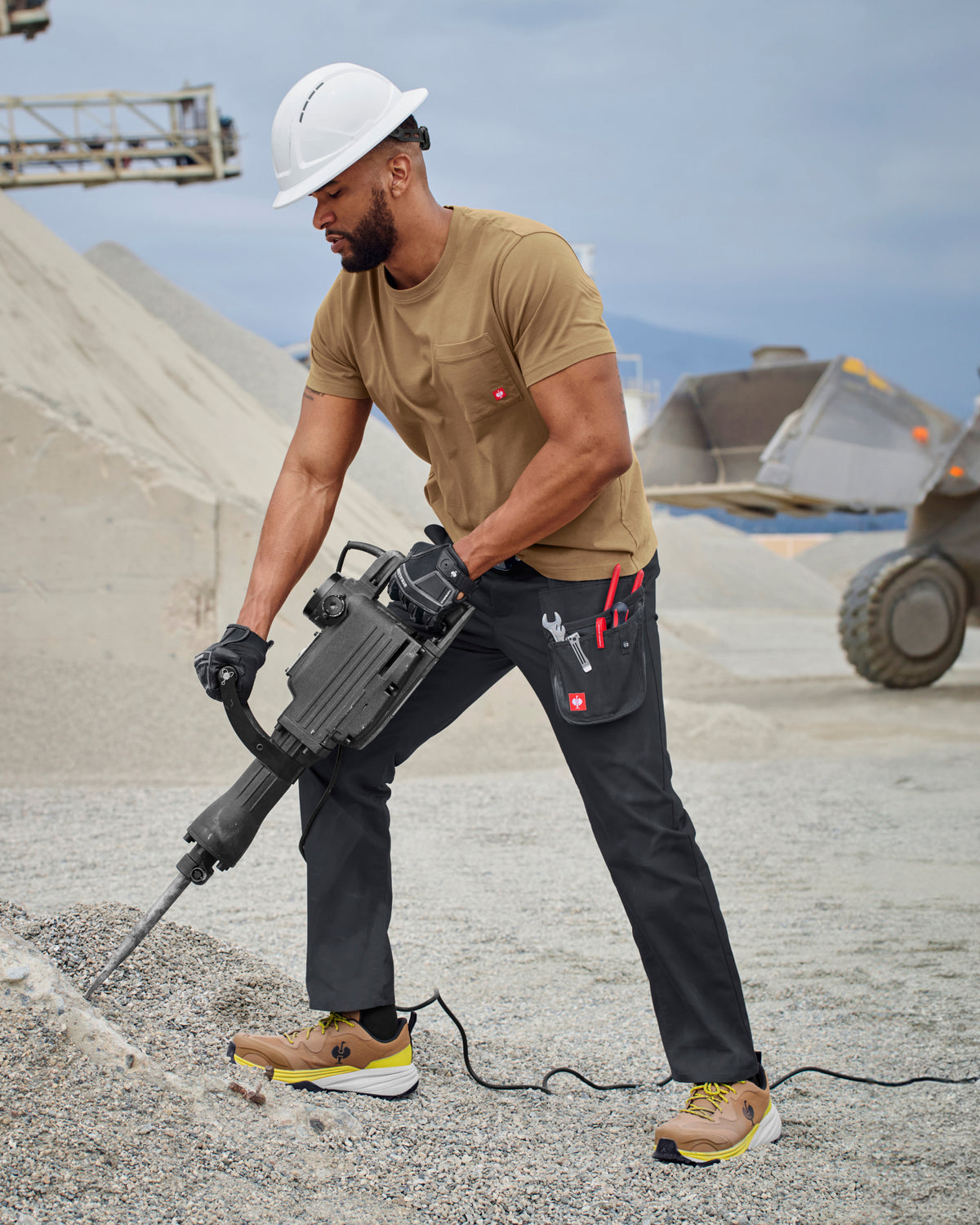 A worker wears the STRAUSS Pocket T-Shirt e.s.iconic in almond brown with work pants near a workshop doorway