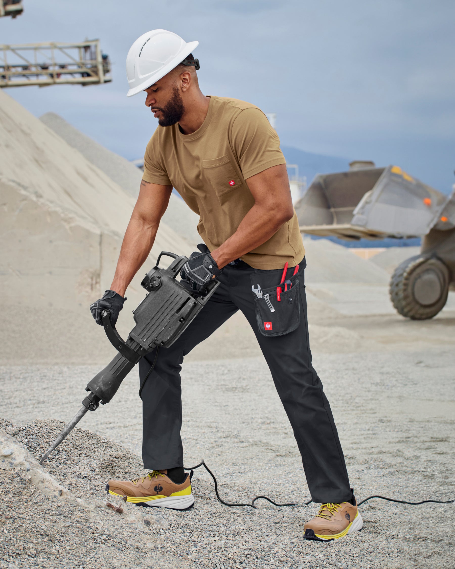 A worker wears the STRAUSS Pocket T-Shirt e.s.iconic in almond brown with work pants near a workshop doorway