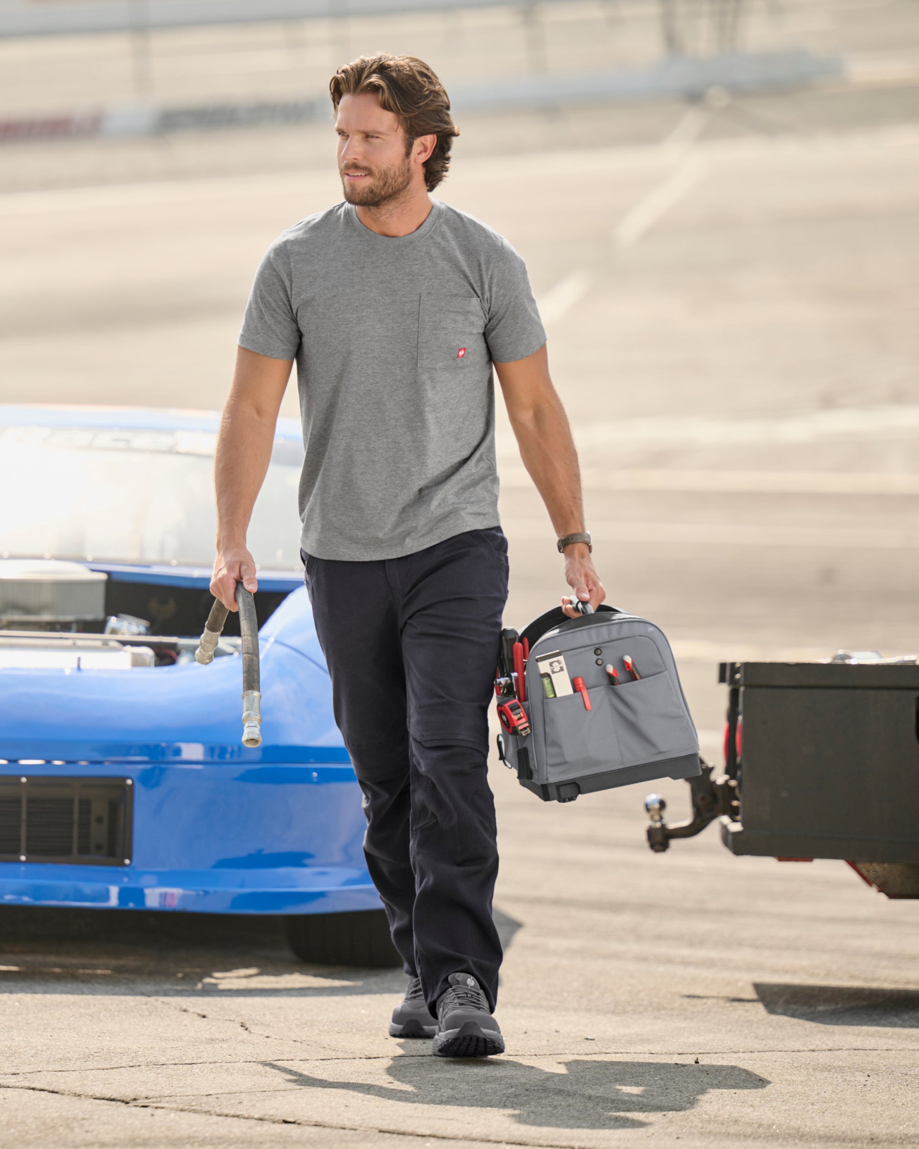A worker wears the STRAUSS Pocket T-Shirt e.s.iconic in gray melange with work pants beside stacked building materials