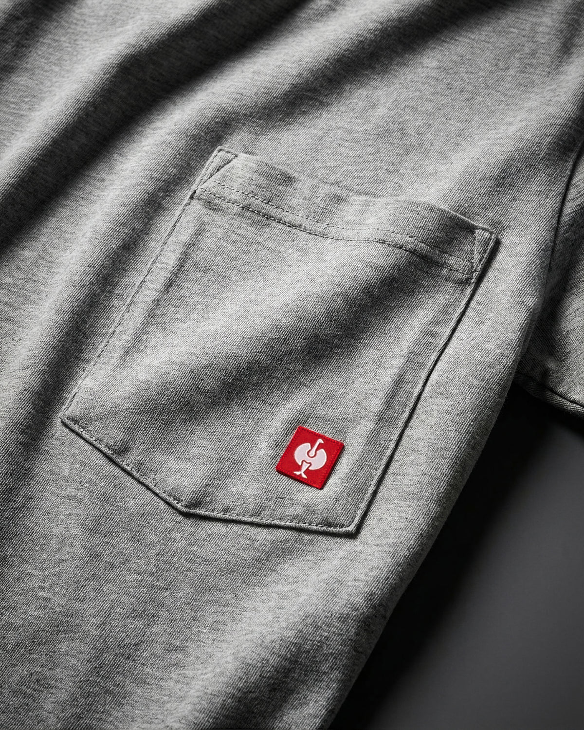 Close-up of the gray melange STRAUSS Pocket T-Shirt e.s.iconic chest pocket with STRAUSS ostrich logo