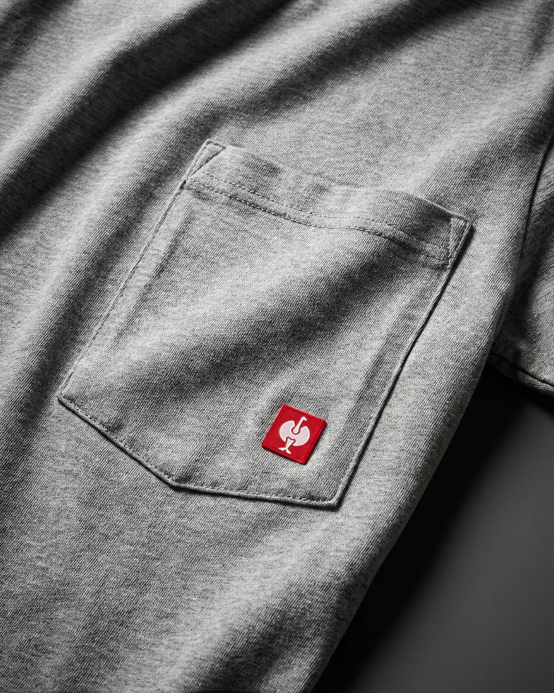 Close-up of the gray melange STRAUSS Pocket T-Shirt e.s.iconic chest pocket with STRAUSS ostrich logo